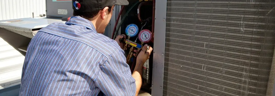 HVAC technician servicing a condenser unit in Brookline